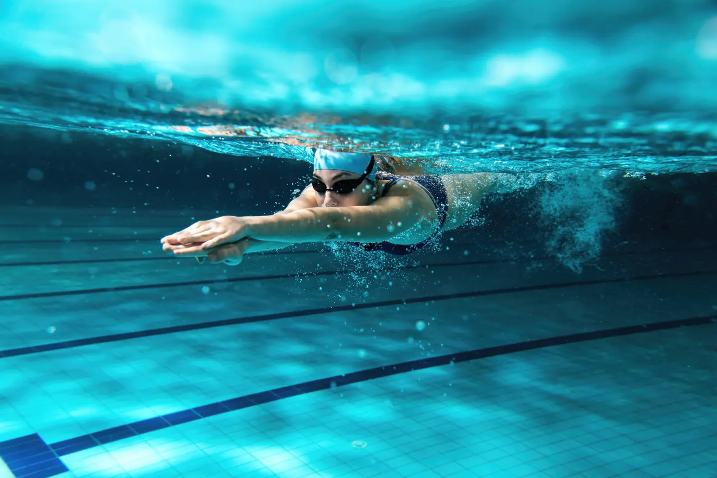 Swimmer gliding underwater in a pool during a survival swimming session